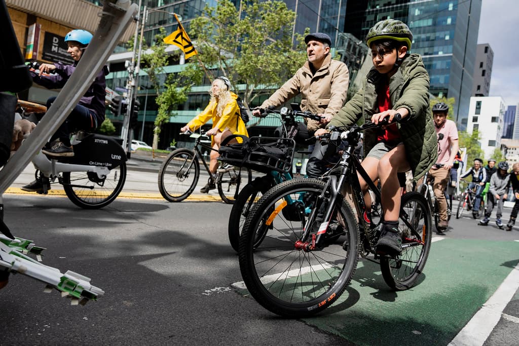 A boy riding in a painted green bike lane through downtown, adults riding alongside