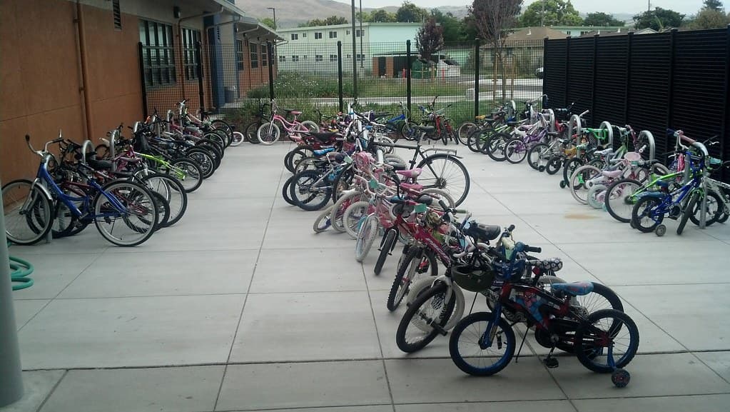 Dozens of kids’ bikes of every size parked outside a school on Bike to School Day